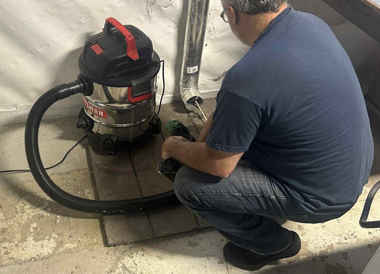 Technician cleaning accessible ductwork with vacuum equipment