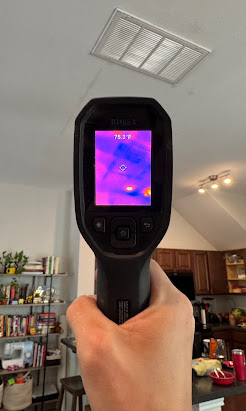 Handheld thermal camera inspecting a ceiling for hidden moisture